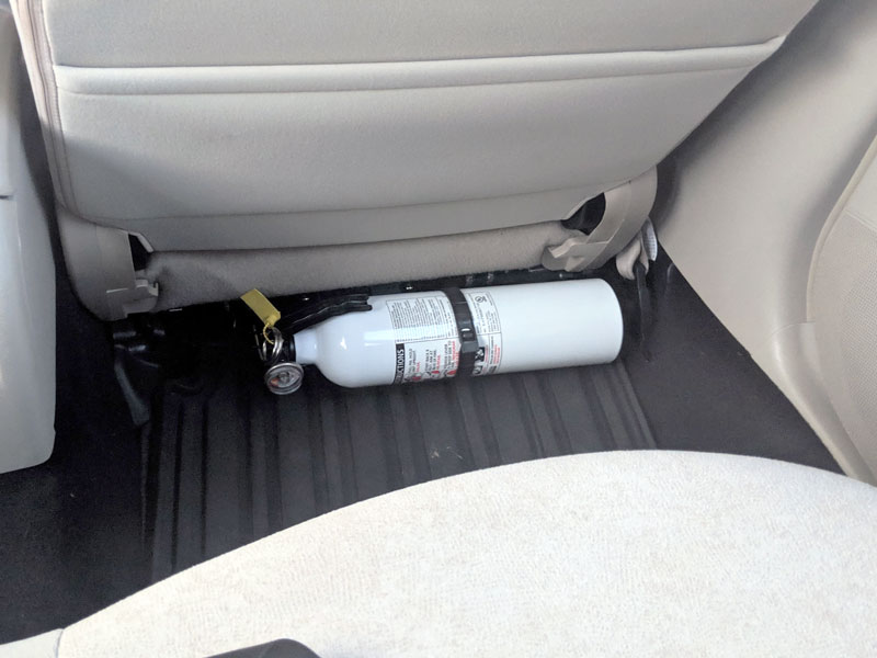 Fire extinguisher installed behind passenger seat
